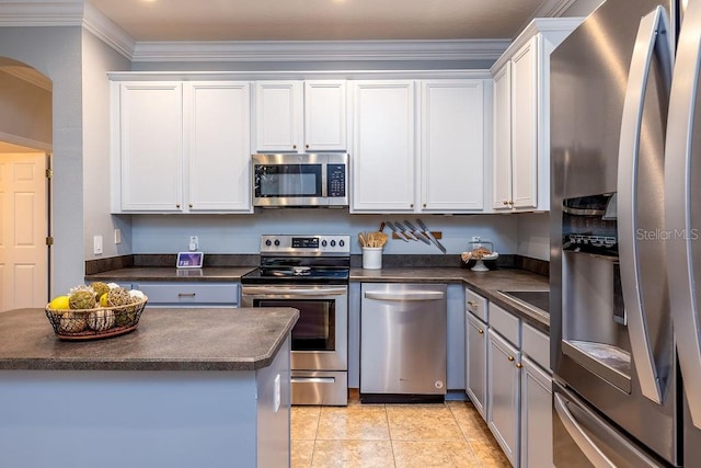 kitchen with crown molding, white cabinets, light tile patterned flooring, and appliances with stainless steel finishes