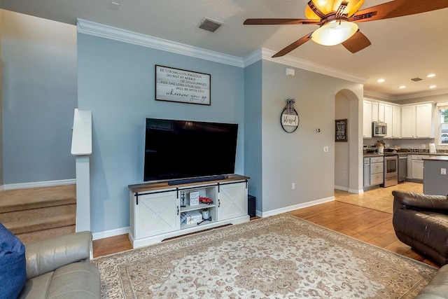 living room featuring ceiling fan, light wood-type flooring, and ornamental molding