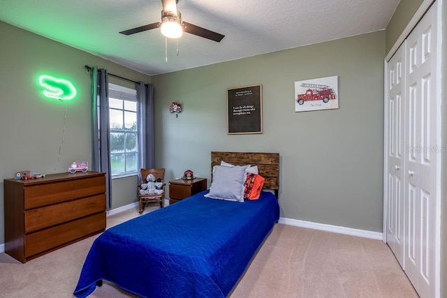 carpeted bedroom featuring ceiling fan, a textured ceiling, and a closet