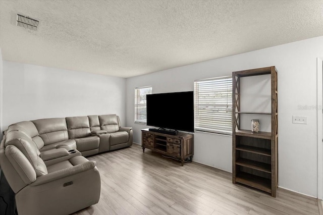 living room with a textured ceiling and light wood-type flooring