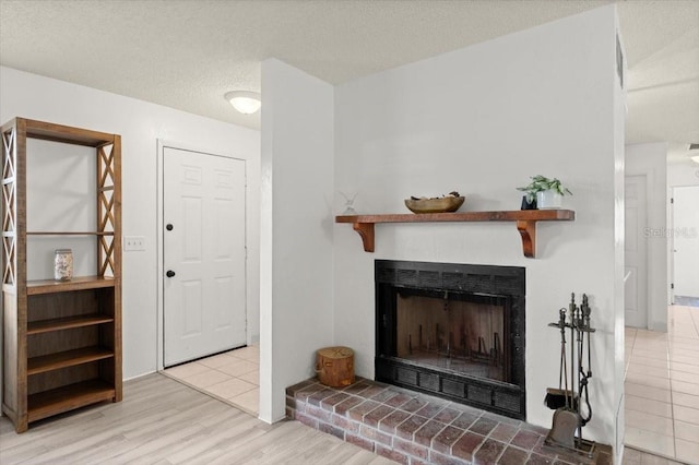 living room featuring a fireplace, a textured ceiling, and light hardwood / wood-style flooring