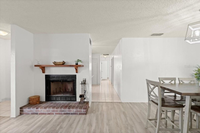 living room with a textured ceiling, light hardwood / wood-style floors, and a fireplace