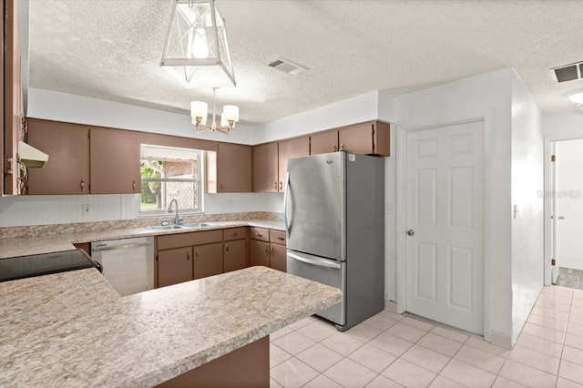 kitchen featuring sink, stainless steel appliances, kitchen peninsula, decorative light fixtures, and light tile patterned floors