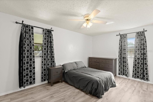 bedroom featuring ceiling fan, light hardwood / wood-style floors, and a textured ceiling