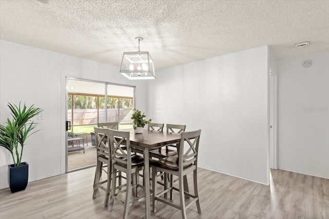 dining room featuring light hardwood / wood-style floors and a textured ceiling