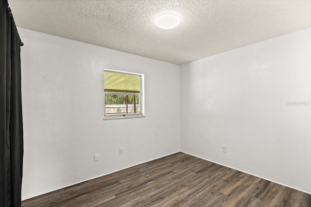 empty room with a textured ceiling and dark wood-type flooring