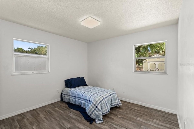 bedroom featuring a textured ceiling, dark wood-type flooring, and multiple windows