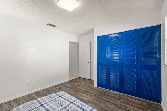 unfurnished bedroom with a closet, dark wood-type flooring, and a textured ceiling