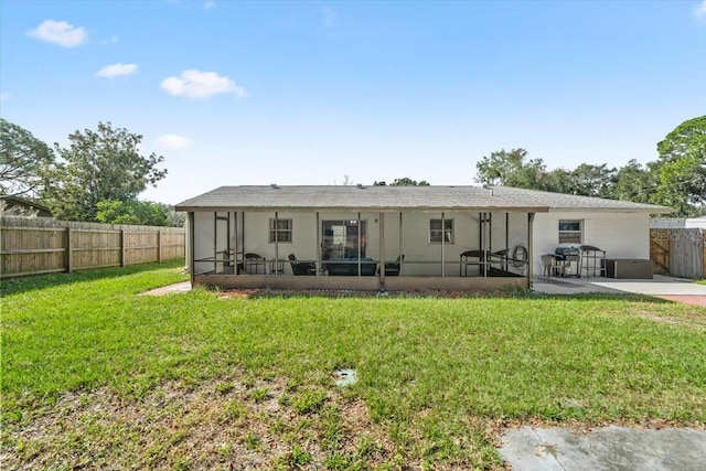 back of house featuring a yard, a patio area, and a sunroom