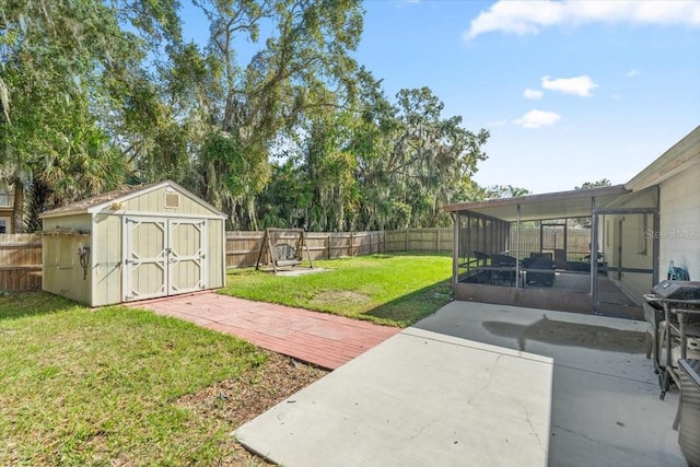 view of yard featuring a sunroom, a storage unit, and a patio