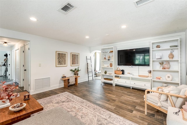 living room featuring a textured ceiling and dark wood-type flooring