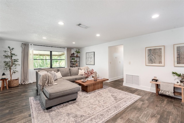 living room with a textured ceiling and dark wood-type flooring