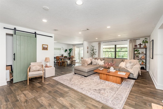 living room with a barn door, dark hardwood / wood-style flooring, and a textured ceiling