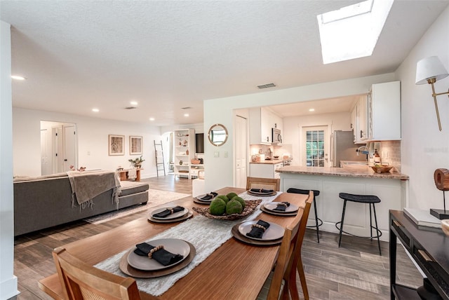 dining room featuring a textured ceiling, dark hardwood / wood-style floors, sink, and a skylight