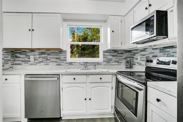 kitchen with decorative backsplash, appliances with stainless steel finishes, sink, hardwood / wood-style floors, and white cabinetry