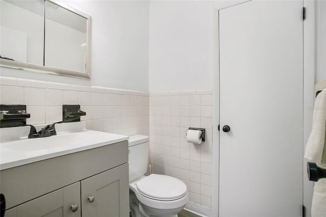 bathroom with vanity, tile walls, and toilet