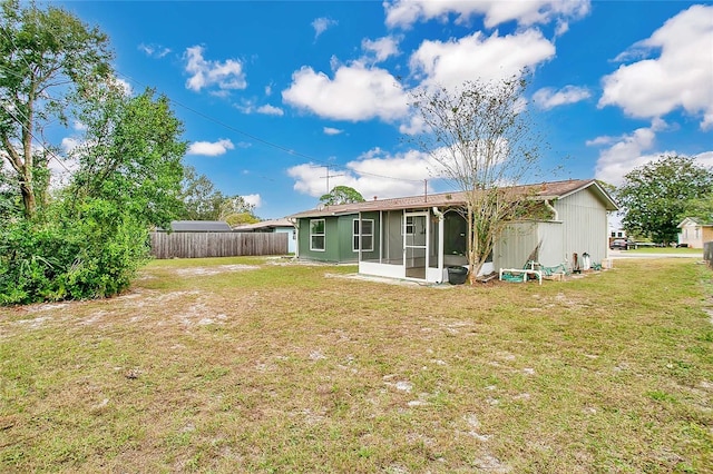 rear view of house featuring a sunroom and a yard