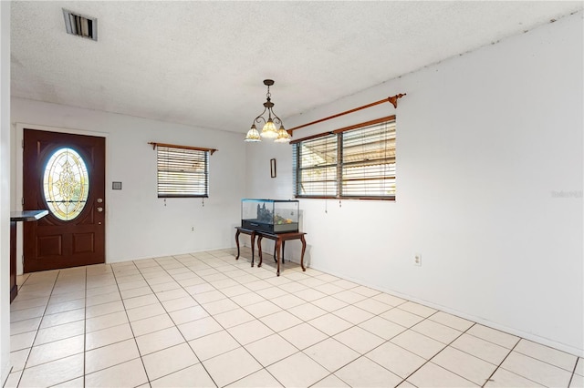 entrance foyer featuring plenty of natural light, light tile patterned floors, a textured ceiling, and a chandelier