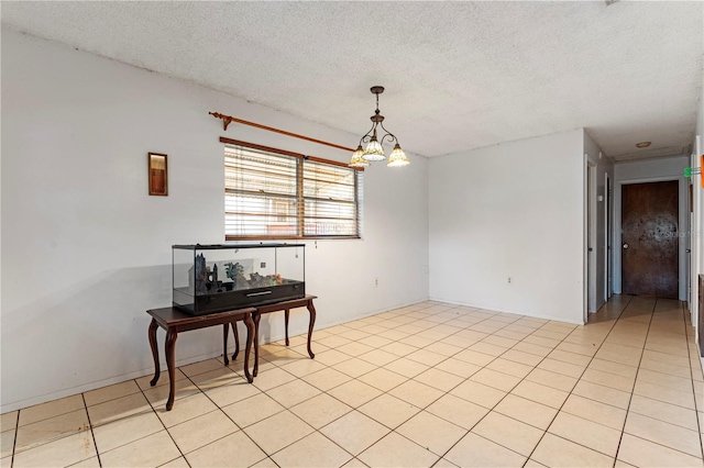 unfurnished room featuring light tile patterned flooring, a textured ceiling, and an inviting chandelier