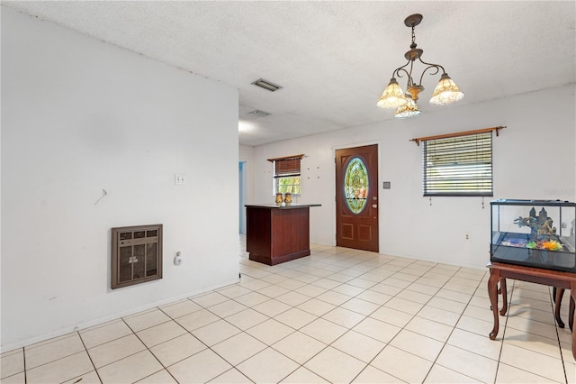 entryway featuring a chandelier, a textured ceiling, heating unit, and light tile patterned flooring