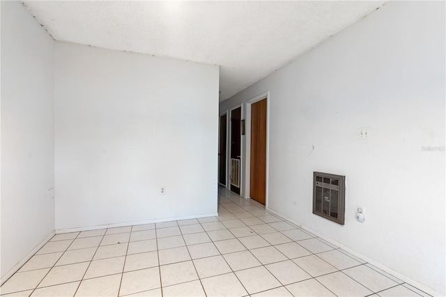 tiled spare room with a textured ceiling and heating unit