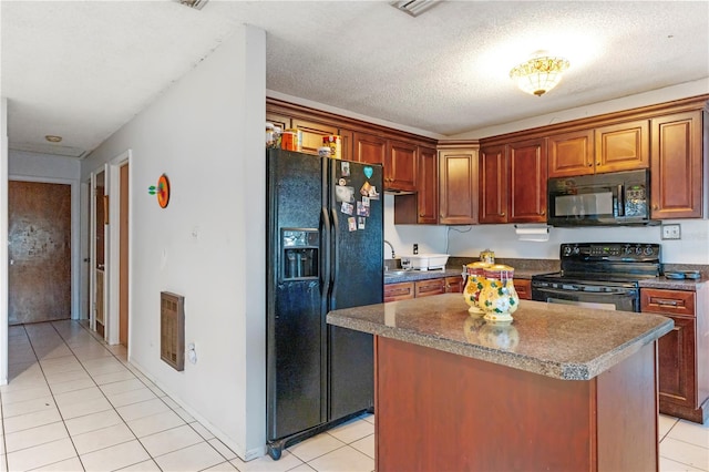 kitchen featuring black appliances, a center island, light tile patterned floors, and a textured ceiling