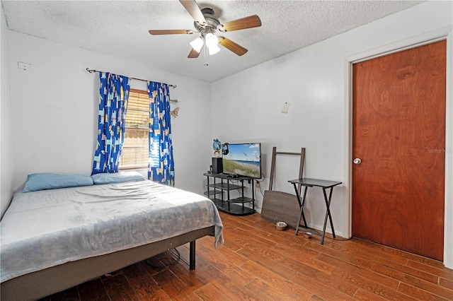 bedroom featuring ceiling fan, wood-type flooring, and a textured ceiling