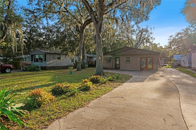 ranch-style home with french doors and a front lawn