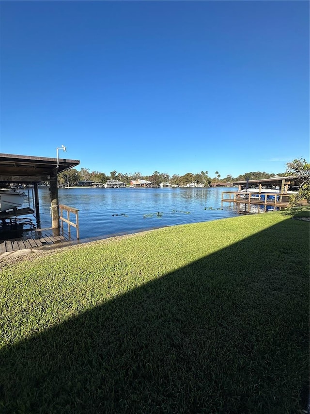 dock area with a lawn and a water view