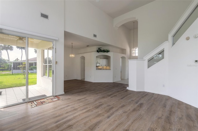 unfurnished living room featuring hardwood / wood-style floors and a towering ceiling