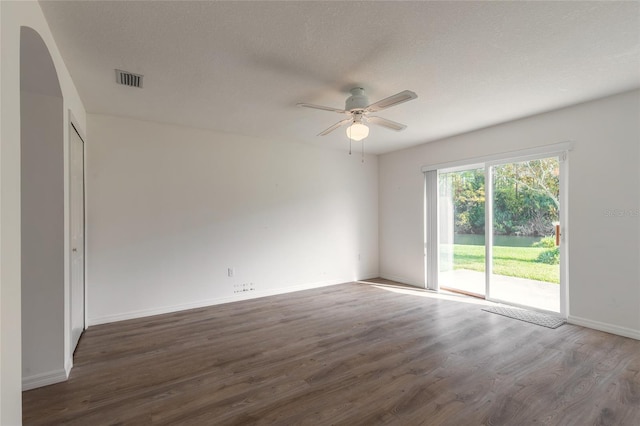 empty room with a textured ceiling, dark hardwood / wood-style flooring, and ceiling fan