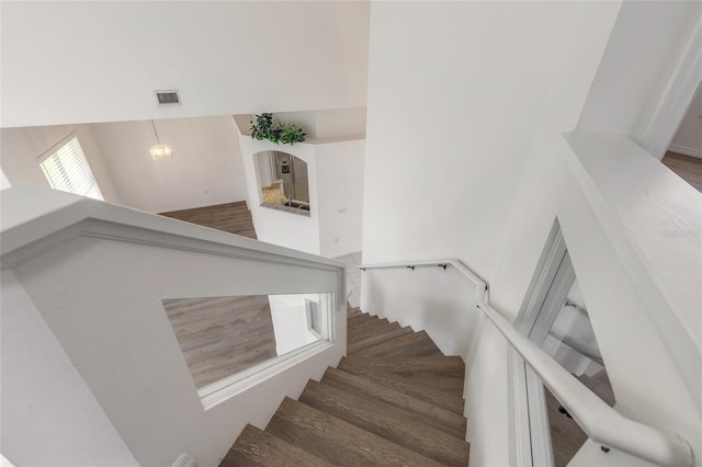 stairs featuring hardwood / wood-style floors and a notable chandelier