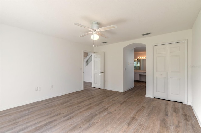 unfurnished bedroom with ceiling fan, light hardwood / wood-style floors, ensuite bathroom, and a closet