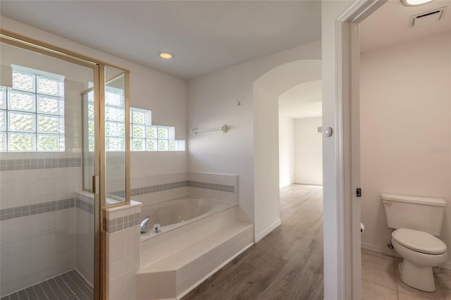 bathroom featuring wood-type flooring, separate shower and tub, and toilet