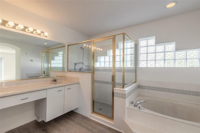 bathroom featuring plus walk in shower, vanity, and hardwood / wood-style flooring