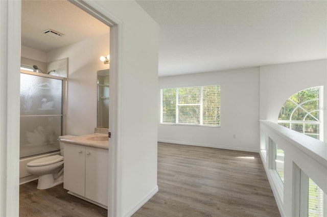 full bathroom featuring hardwood / wood-style floors, vanity, enclosed tub / shower combo, and toilet