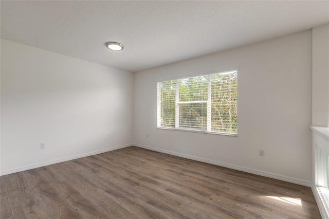 unfurnished room with wood-type flooring and a textured ceiling