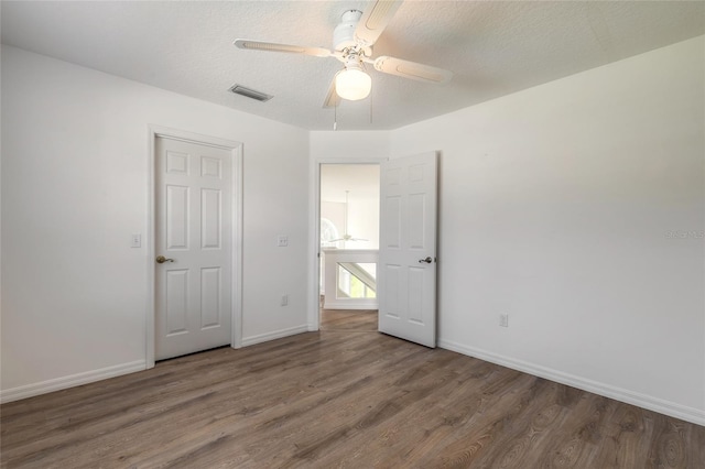 unfurnished bedroom featuring ceiling fan, dark hardwood / wood-style floors, and a textured ceiling