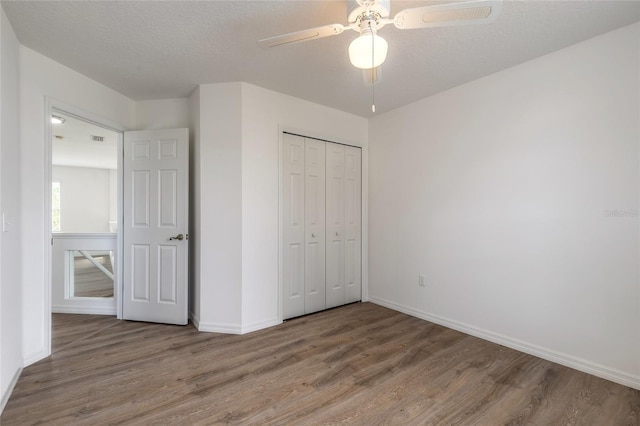 unfurnished bedroom featuring a closet, ceiling fan, hardwood / wood-style floors, and a textured ceiling