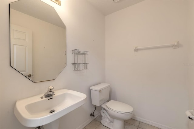 bathroom with toilet, tile patterned floors, and sink