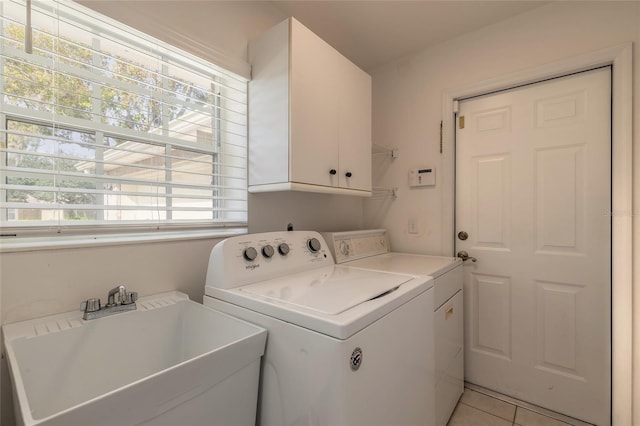 laundry area featuring separate washer and dryer, sink, light tile patterned floors, and cabinets