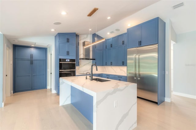 kitchen with built in fridge, blue cabinets, sink, decorative backsplash, and decorative light fixtures