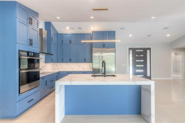 kitchen featuring a kitchen island with sink, sink, wall chimney exhaust hood, light stone counters, and stainless steel appliances