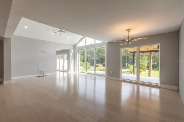 unfurnished room featuring light hardwood / wood-style flooring, a healthy amount of sunlight, and ceiling fan with notable chandelier