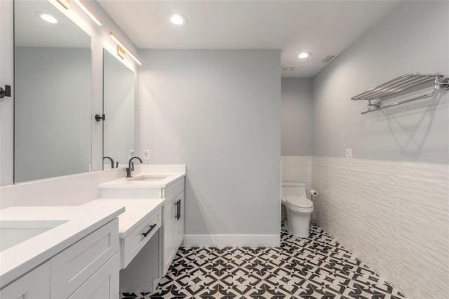 bathroom with tile patterned flooring, vanity, tile walls, and toilet