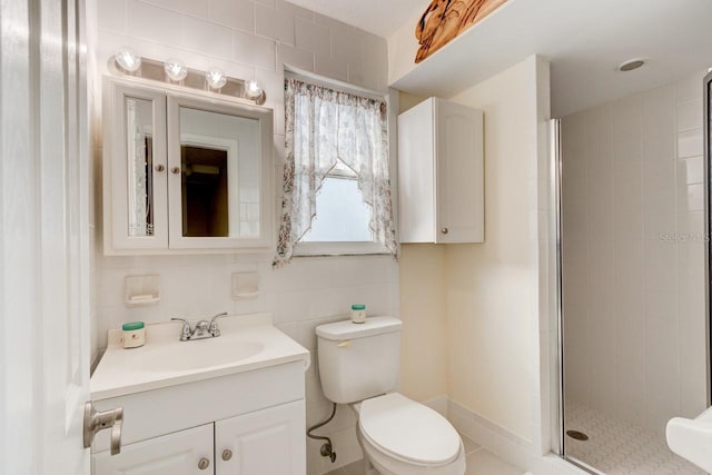 bathroom featuring vanity, toilet, a shower with shower door, and tile walls