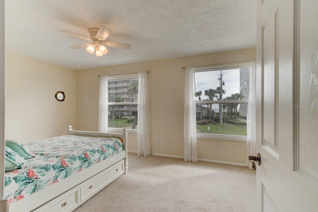 carpeted bedroom with ceiling fan and a textured ceiling