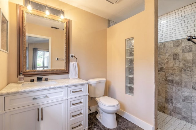 bathroom with tile patterned flooring, vanity, toilet, and tiled shower