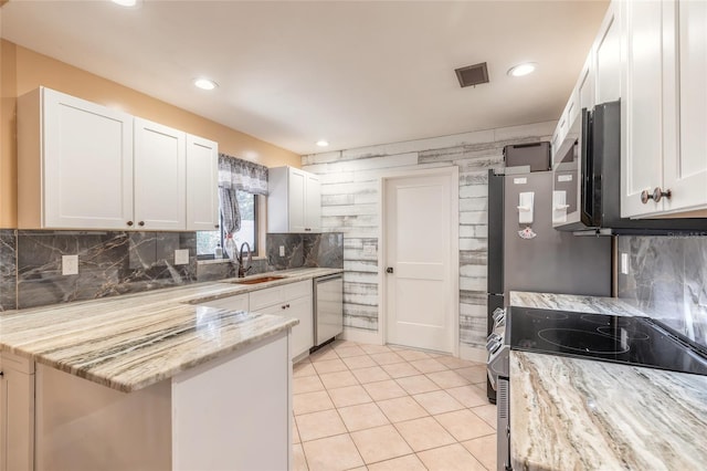 kitchen featuring light stone countertops, appliances with stainless steel finishes, sink, light tile patterned floors, and white cabinetry