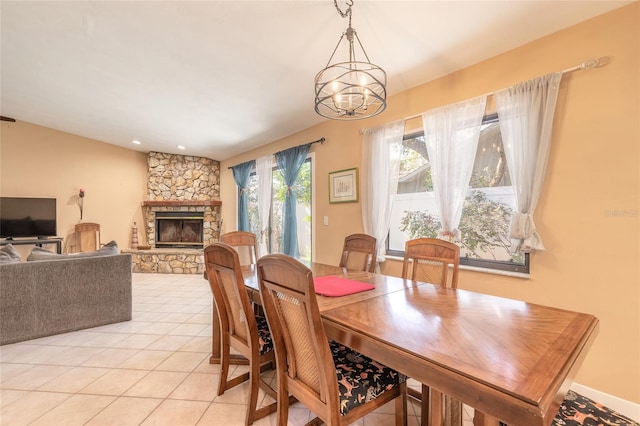 dining area with a stone fireplace, light tile patterned flooring, and a notable chandelier